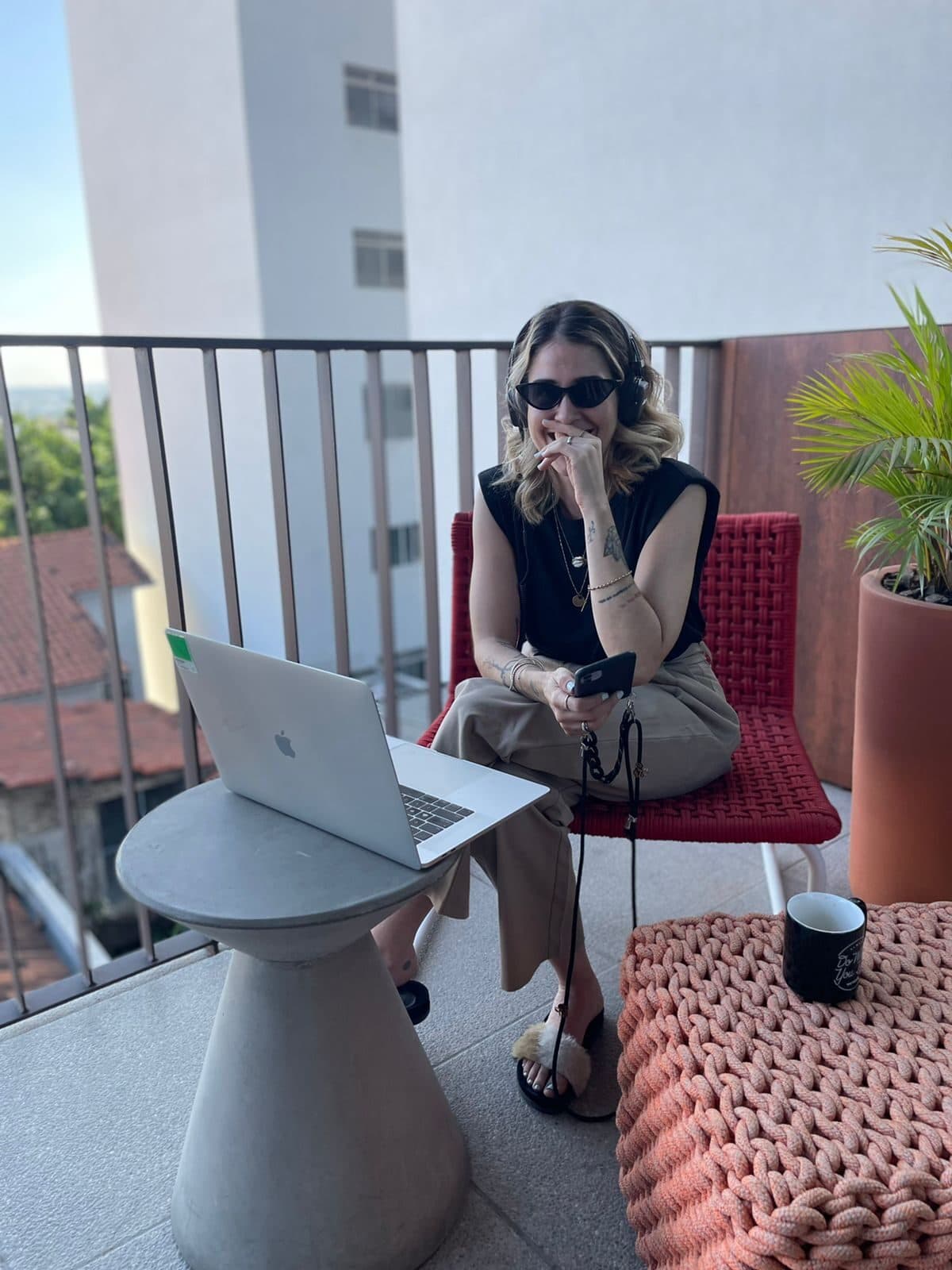 Giorgia trabalhando na varanda da agência, em reunião remota