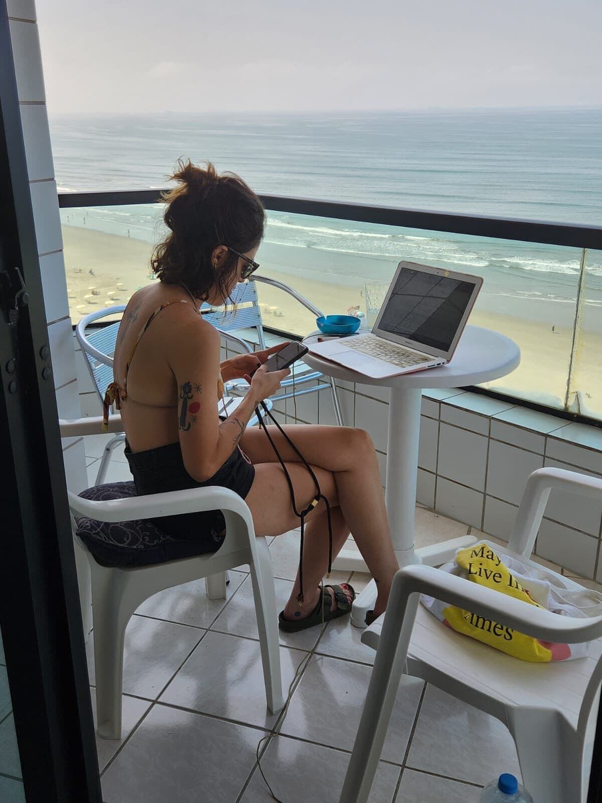 Giorgia trabalhando em uma varanda com o mar ao fundo